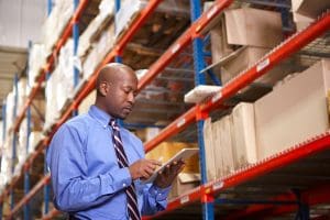 Warehouse manager looking at tablet and reviewing storage procedures